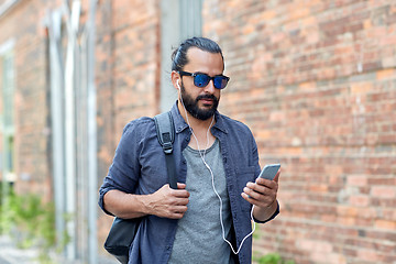 Image showing man with earphones and smartphone walking in city