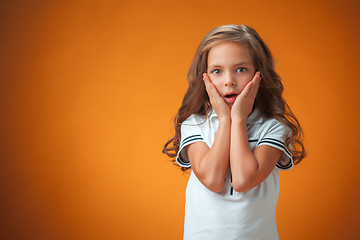 Image showing The cute surprised little girl on orange background