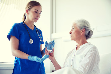 Image showing nurse giving medicine to senior woman at hospital