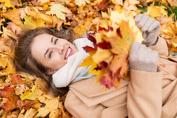 Image showing beautiful happy woman lying on autumn leaves