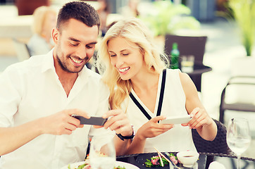 Image showing happy couple with smatphone photographing food