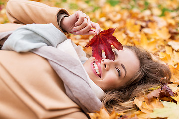 Image showing beautiful happy woman lying on autumn leaves