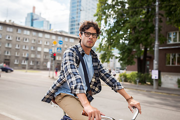 Image showing young hipster man with bag riding fixed gear bike