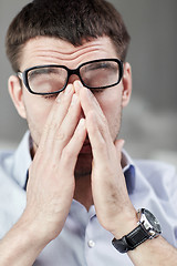 Image showing tired businessman with eyeglasses at office 