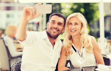 Image showing happy couple taking selfie with smatphone at cafe