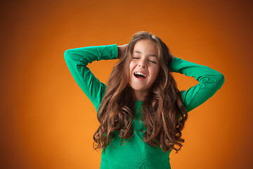 Image showing The cute cheerful little girl on orange background