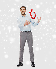 Image showing happy young man with christmas gift box over snow