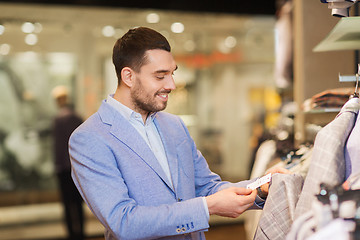 Image showing happy young man choosing clothes in clothing store