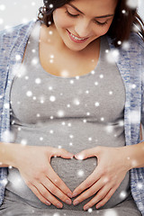 Image showing happy pregnant woman making heart gesture at home