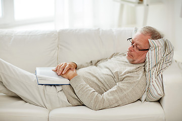 Image showing senior man sleeping on sofa with book at home