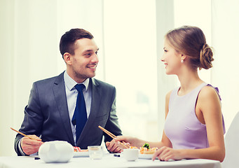 Image showing smiling couple eating sushi at restaurant