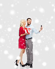 Image showing happy couple with smartphone and christmas gifts