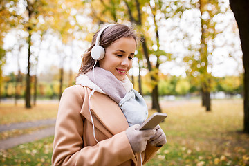 Image showing woman with smartphone and earphones in autumn park