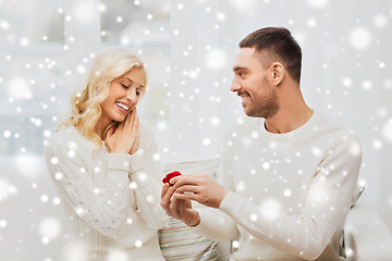 Image showing happy man giving engagement ring to woman at home