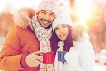 Image showing happy couple with tea cups over winter landscape