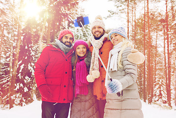 Image showing smiling friends with smartphone in winter forest