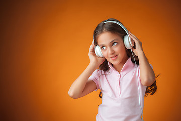 Image showing The cute cheerful little girl on orange background