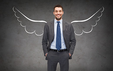 Image showing happy businessman with angel wings over gray