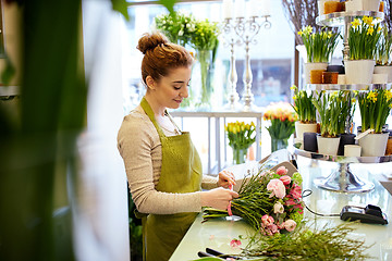 Image showing smiling florist woman making bunch at flower shop