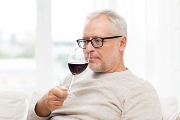Image showing senior man drinking red wine from glass at home