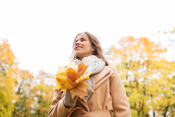 Image showing beautiful woman with maple leaves in autumn park