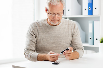 Image showing senior man with glucometer checking blood sugar