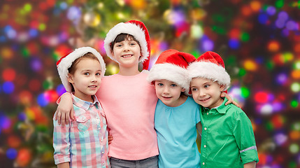 Image showing happy little children in santa hats hugging
