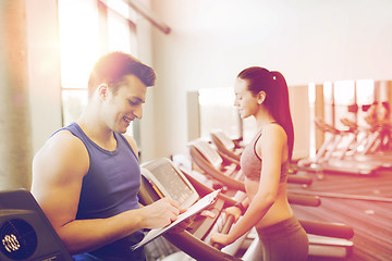 Image showing happy woman with trainer on treadmill in gym