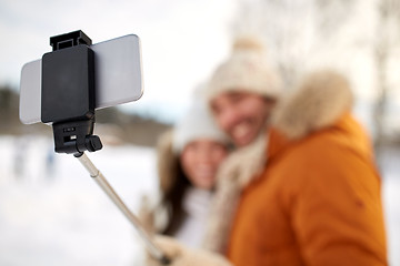 Image showing happy couple taking selfie by smartphone in winter