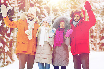 Image showing group of friends waving hands in winter forest