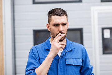 Image showing auto mechanic smoking cigarette at car workshop