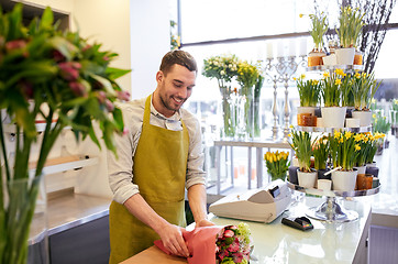 Image showing florist wrapping flowers in paper at flower shop