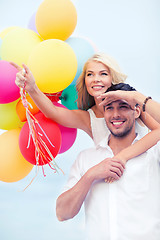 Image showing couple with colorful balloons at seaside