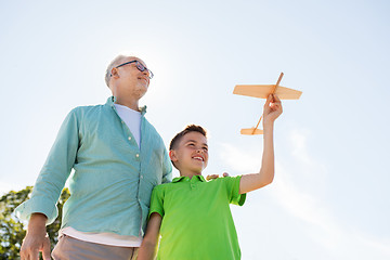 Image showing senior man and boy with toy airplane over sky