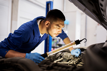 Image showing mechanic man with lamp repairing car at workshop