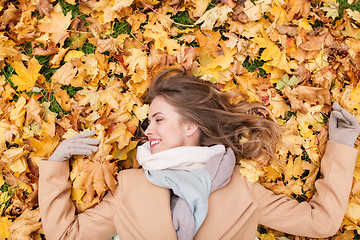 Image showing beautiful happy woman lying on autumn leaves