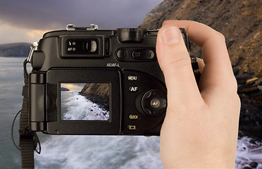 Image showing Digital Camera photo in a hand isolated on withe background. lcd screen and background can be easily edited