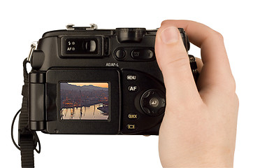 Image showing Digital Camera photo in a hand isolated on withe background. lcd screen and background can be easily edited