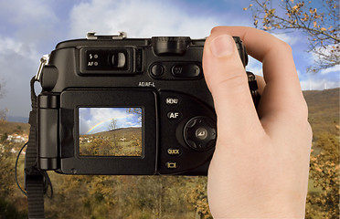 Image showing Digital Camera photo in a hand isolated on withe background. lcd screen and background can be easily edited