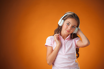 Image showing The cute cheerful little girl on orange background