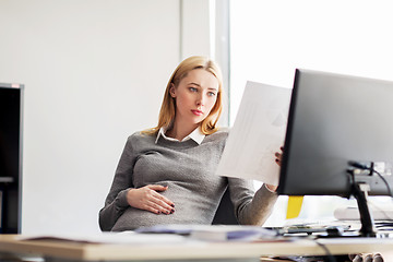 Image showing pregnant businesswoman reading papers at office