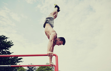 Image showing young man exercising on parallel bars outdoors