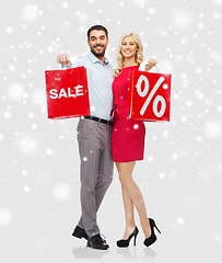 Image showing happy couple with red shopping bags over snow