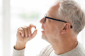 Image showing close up of senior man taking medicine pill