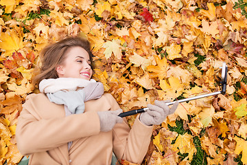 Image showing woman on autumn leaves taking selfie by smartphone