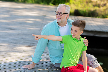 Image showing grandfather and grandson sitting on river berth