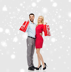 Image showing happy couple with red shopping bags over snow