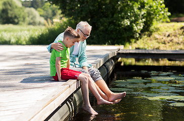 Image showing grandfather and grandson sitting on river berth