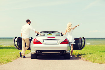 Image showing happy man and woman near cabriolet car at sea