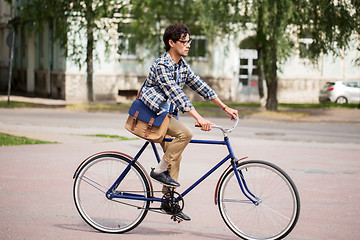 Image showing young hipster man with bag riding fixed gear bike